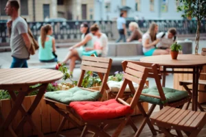Close up of an outdoor café chairs and tables, with Prague's neighbourhood scene in the background.