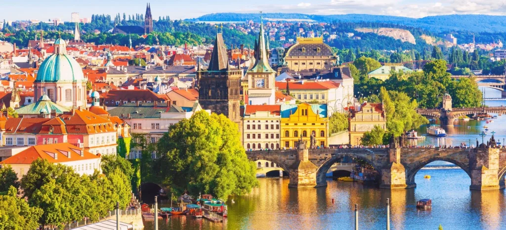 A vista in Prague showcases two bridges spanning the Vltava River, with awe-inspiring historical structures forming the background.